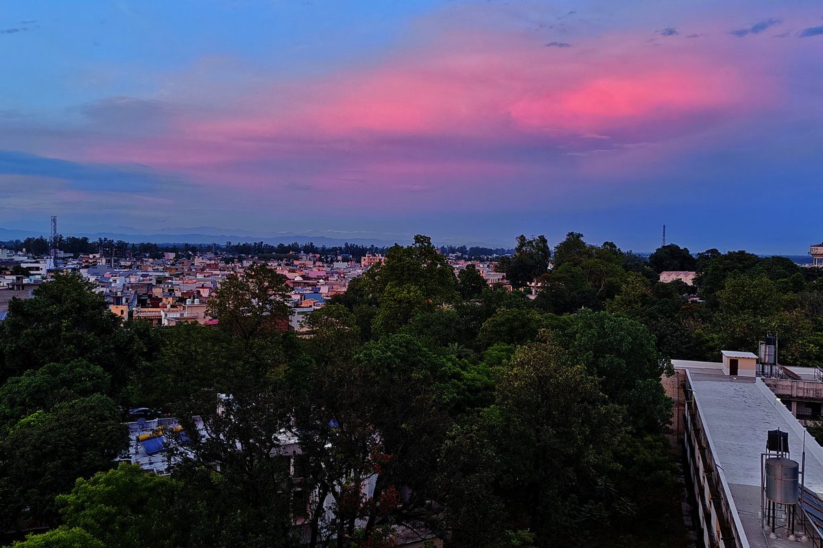 Rooftop view of a city skyline under a pink and purple dusk sky